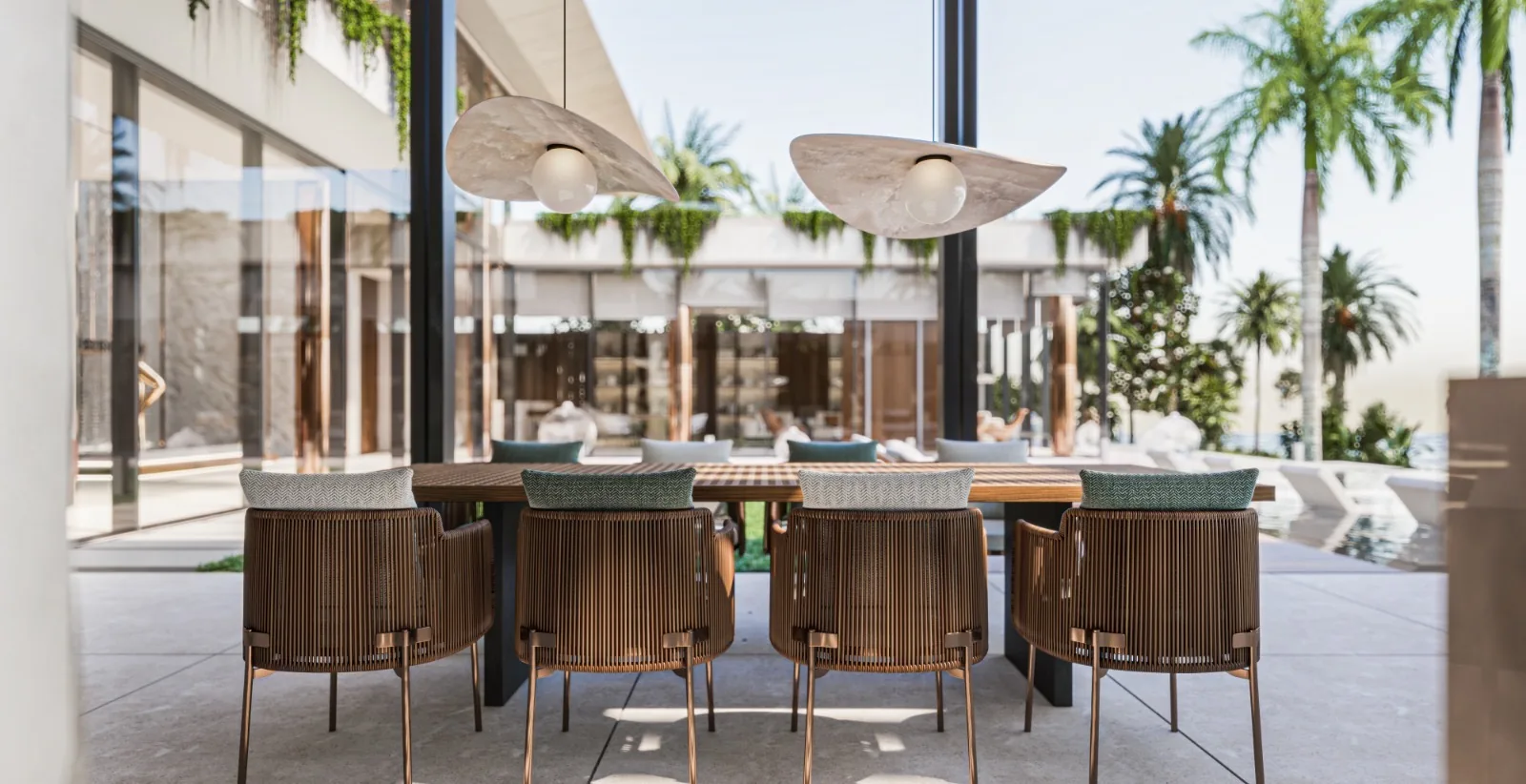 Outdoor dining courtyard with woven chairs and stone pendant lights among palms.