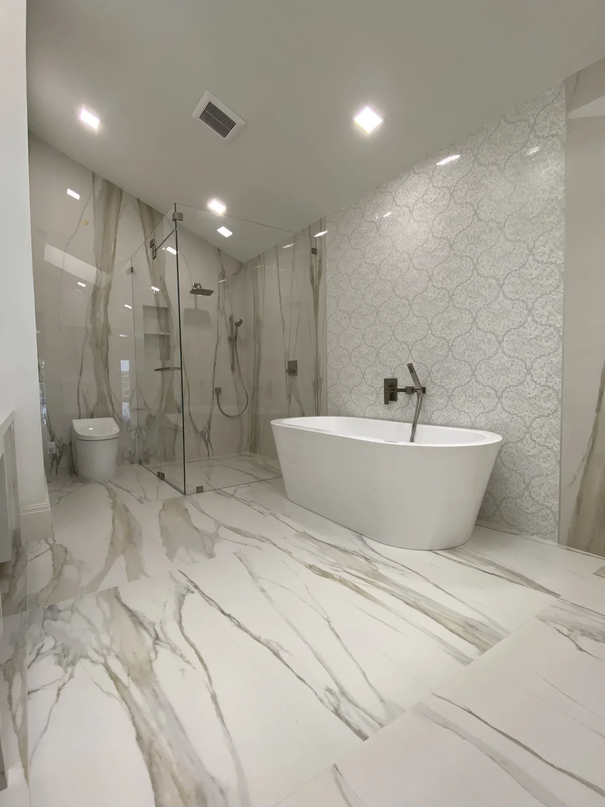 Marble flooring, freestanding tub, walk-in shower, contemporary fixtures.