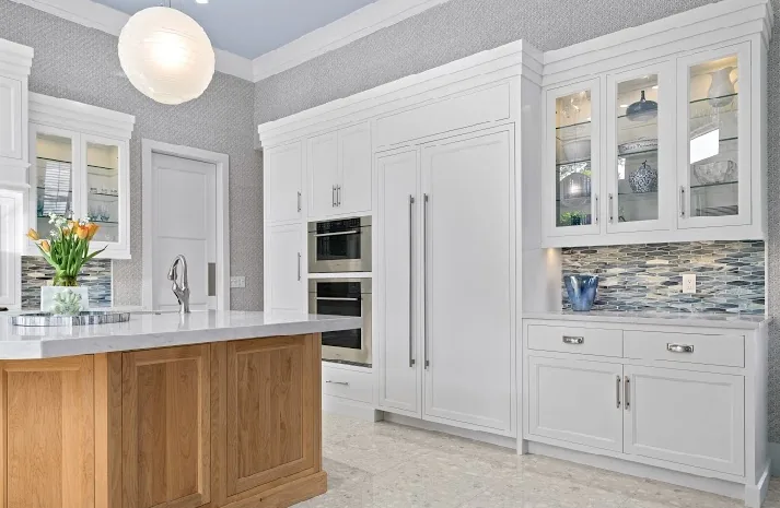 White cabinetry, wood island, stainless steel appliances, and mosaic backsplash.
