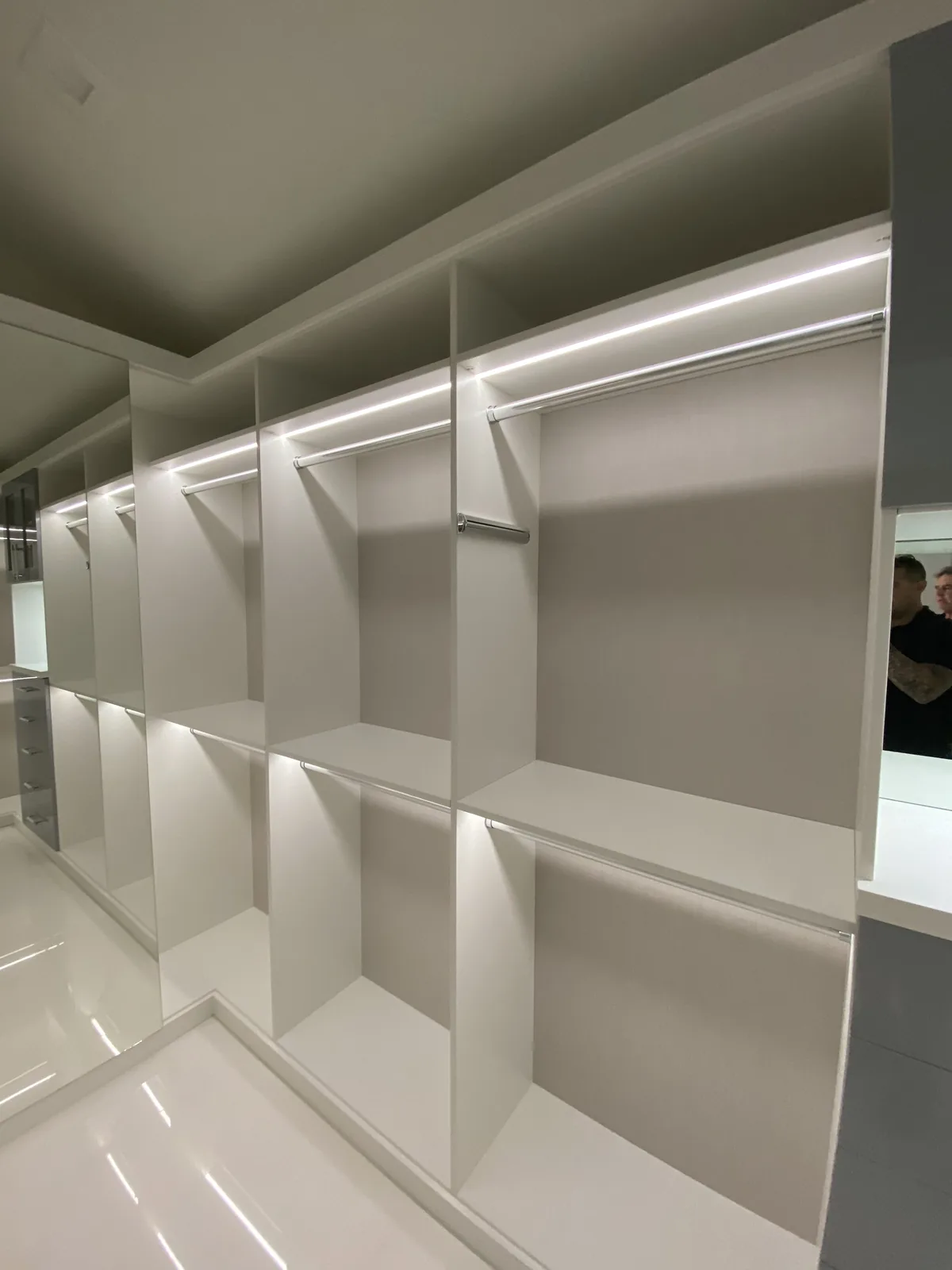 White built-in shelving, LED lighting, and hanging rods.