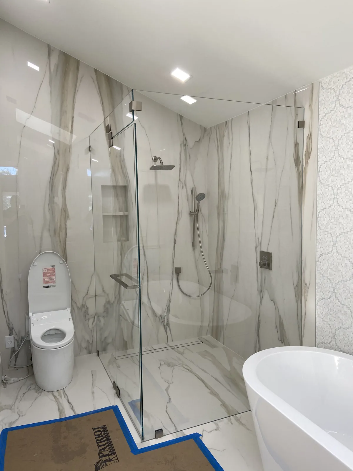 Marble tile shower enclosure, freestanding tub, contemporary fixtures.