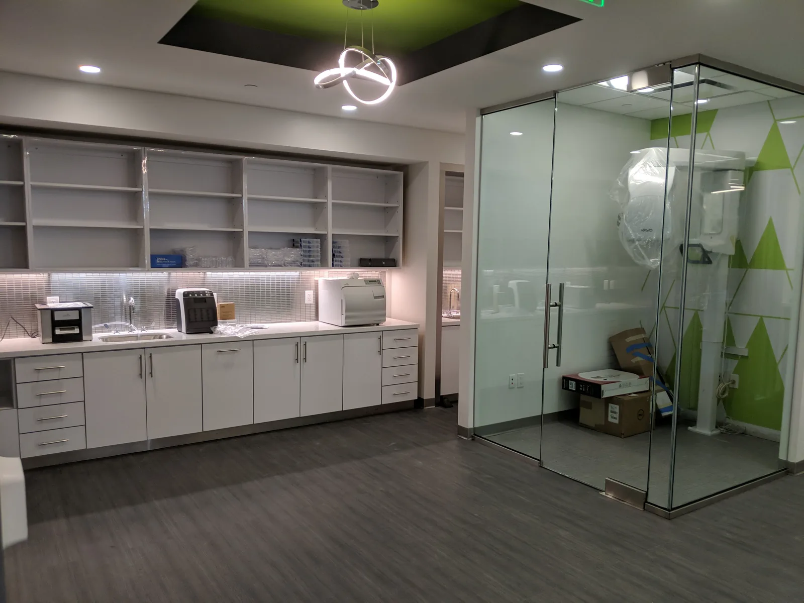 Clinic breakroom with white cabinetry, stainless appliances, frosted glass partition.