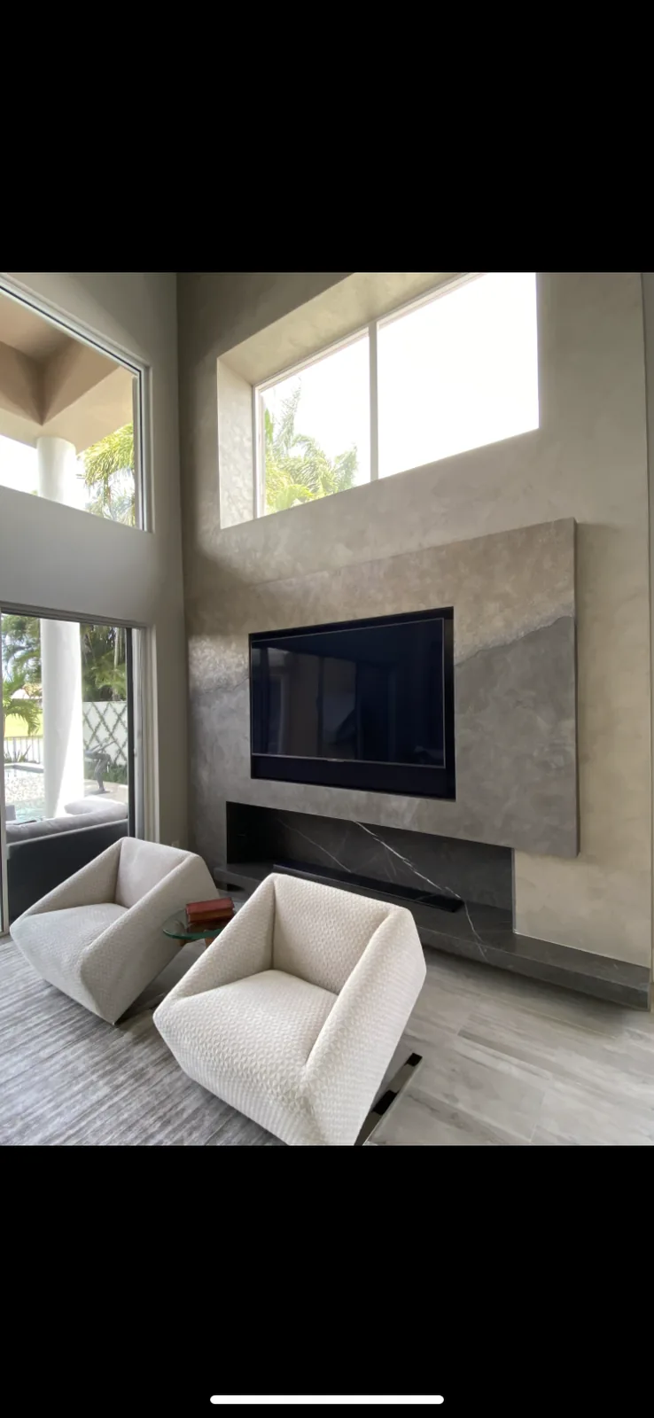 High-ceiling living room with concrete feature wall and mounted flat-screen.