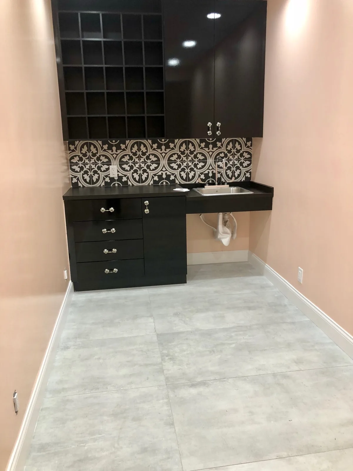 Bathroom vanity with black cabinetry, decorative tile backsplash, marble floor.