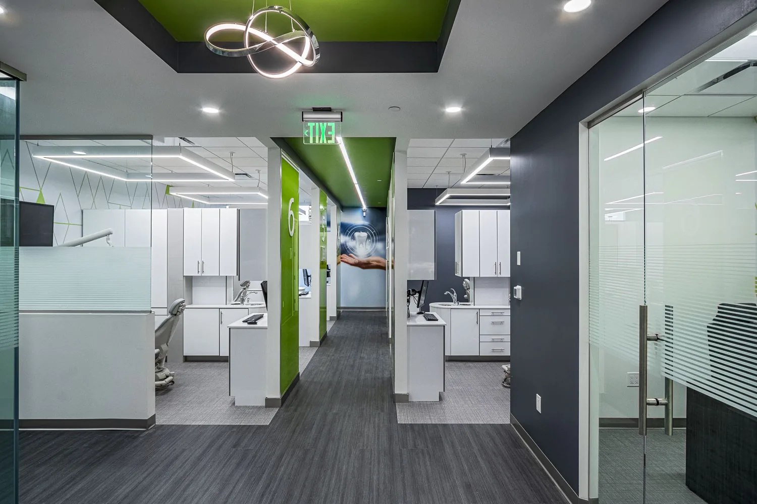 Dental office with white cabinetry, green accents, and glass partitions.