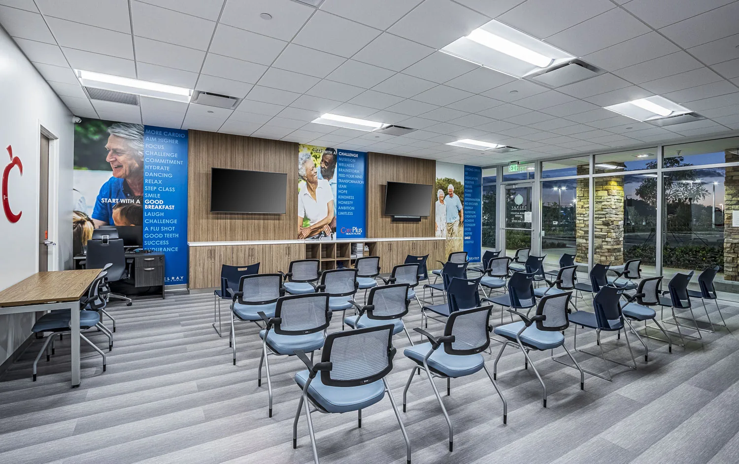 Fitness facility with rows of mesh chairs, wall-mounted displays, motivational signage.