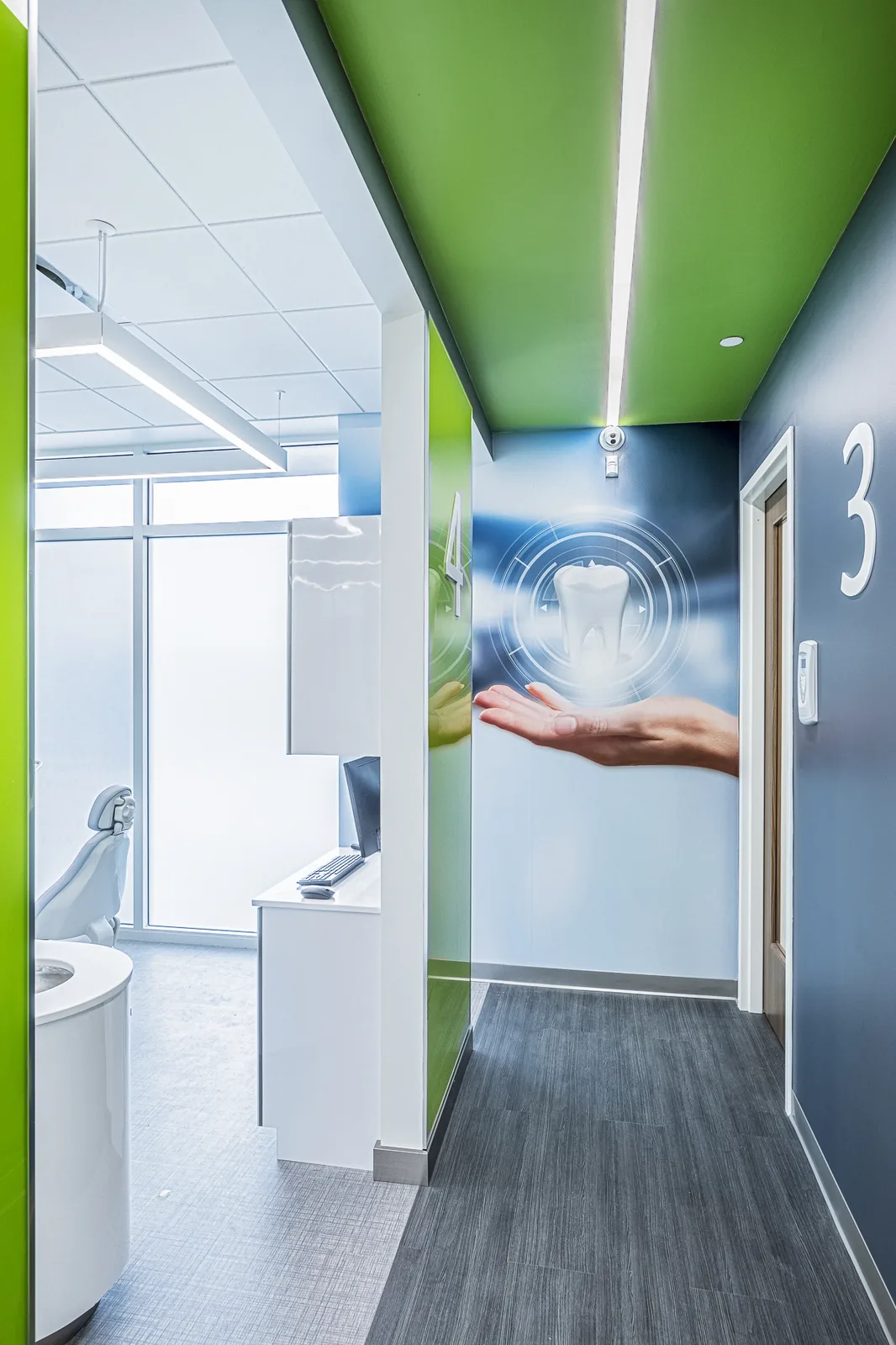 Medical office hallway with green and blue walls and room number signage.